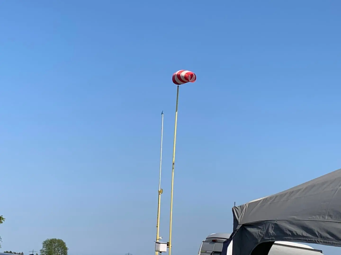Ein strammer, weiß-roter Windsack vor blauem Himmel.
