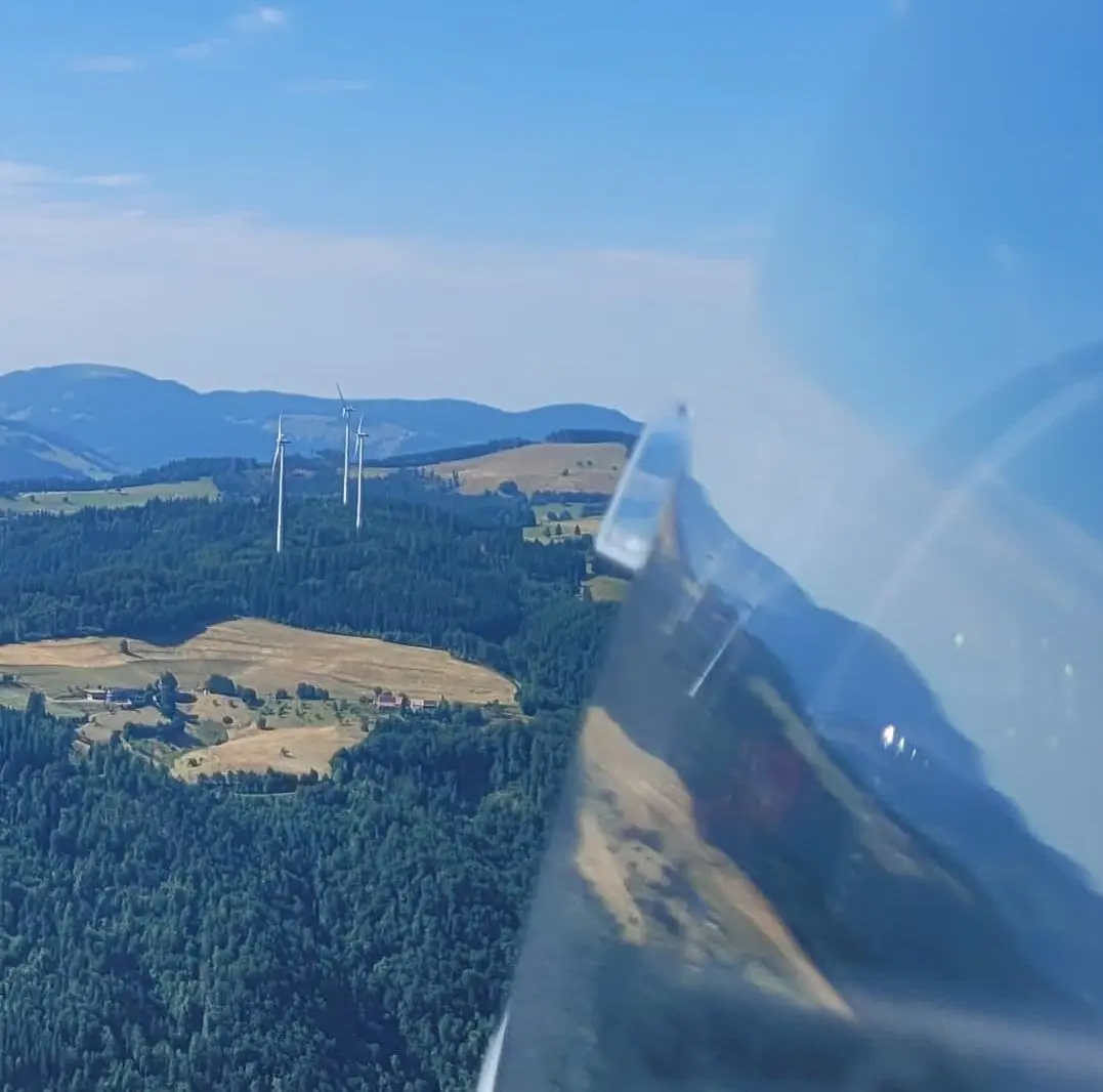 Windräder auf einem Hang oben.