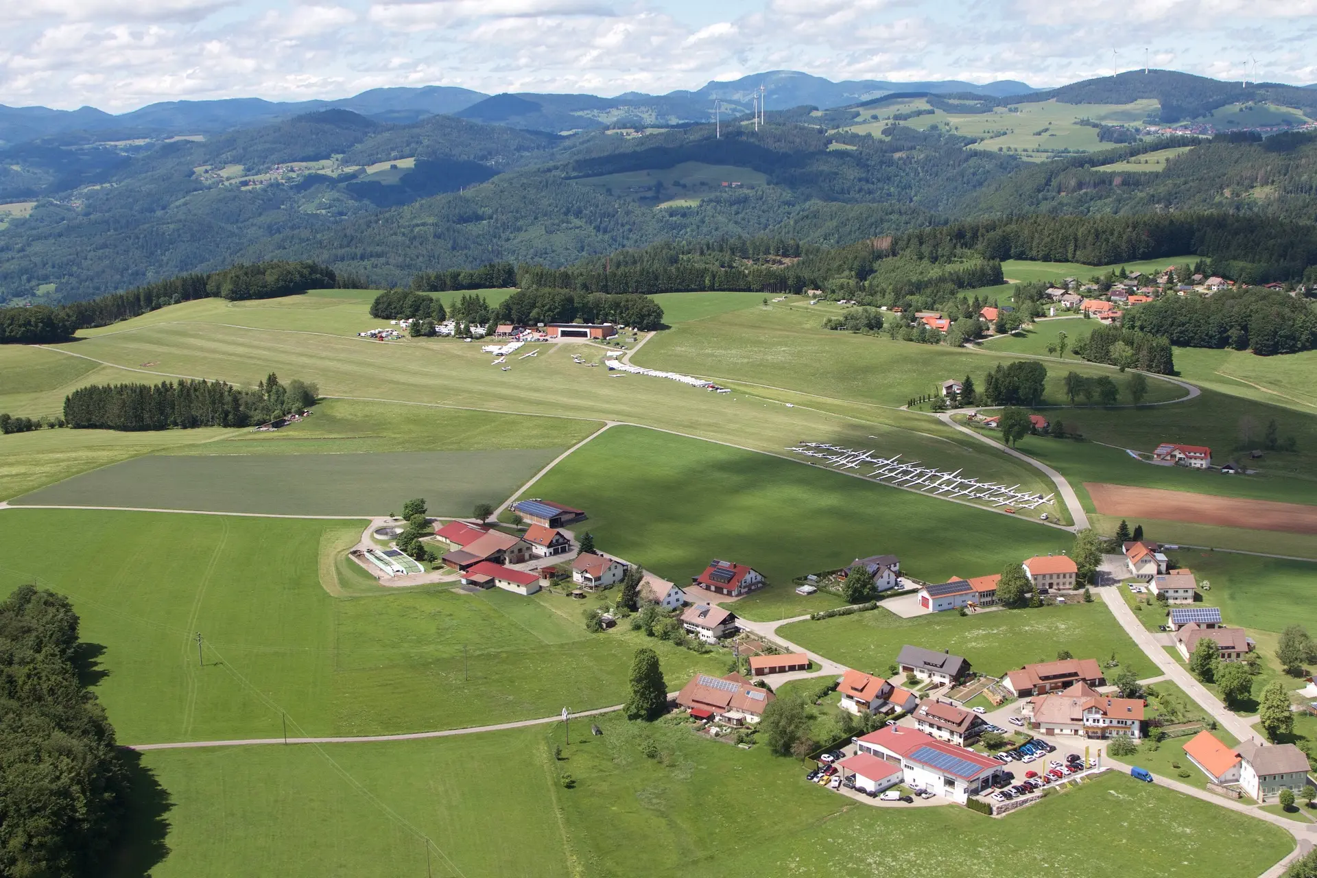 Luftaufnahme des Flugplatzes Hütten-Hotzenwald mit Hangar, Piste und dem Ort