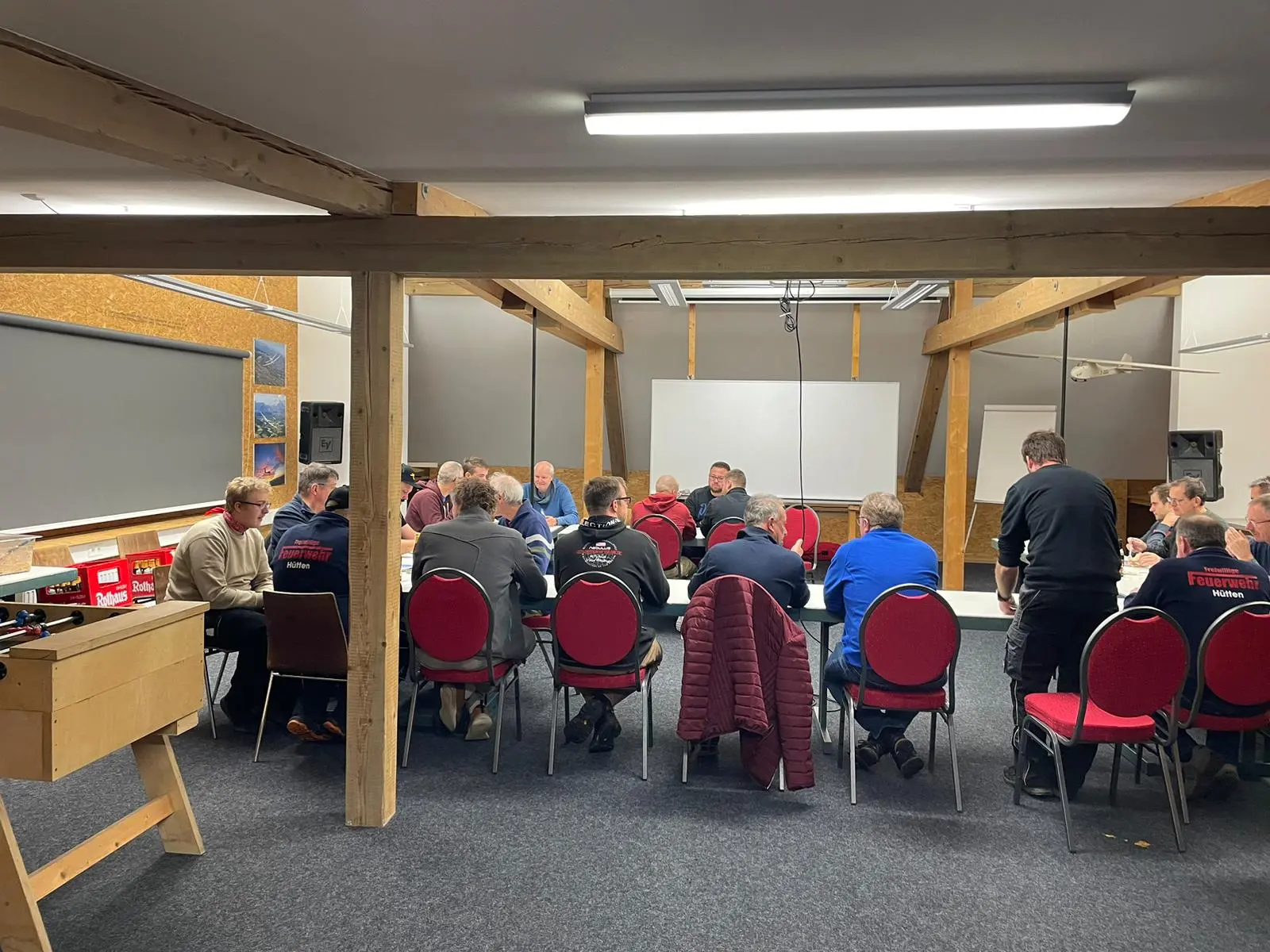 Schulungsraum im Vereinsheim mit Holzbalken, Tischen und roten Stühlen bei einer Besprechung