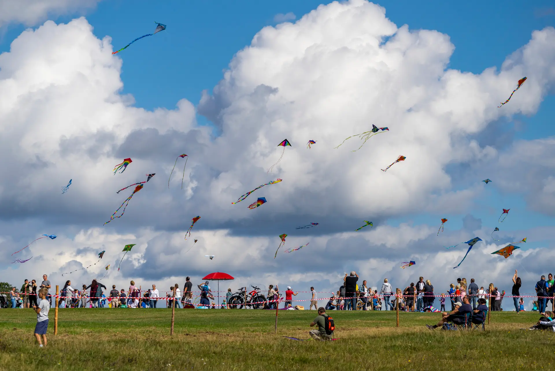 Bunte Drachen vor einer großen Wolke beim Flugplatzfest